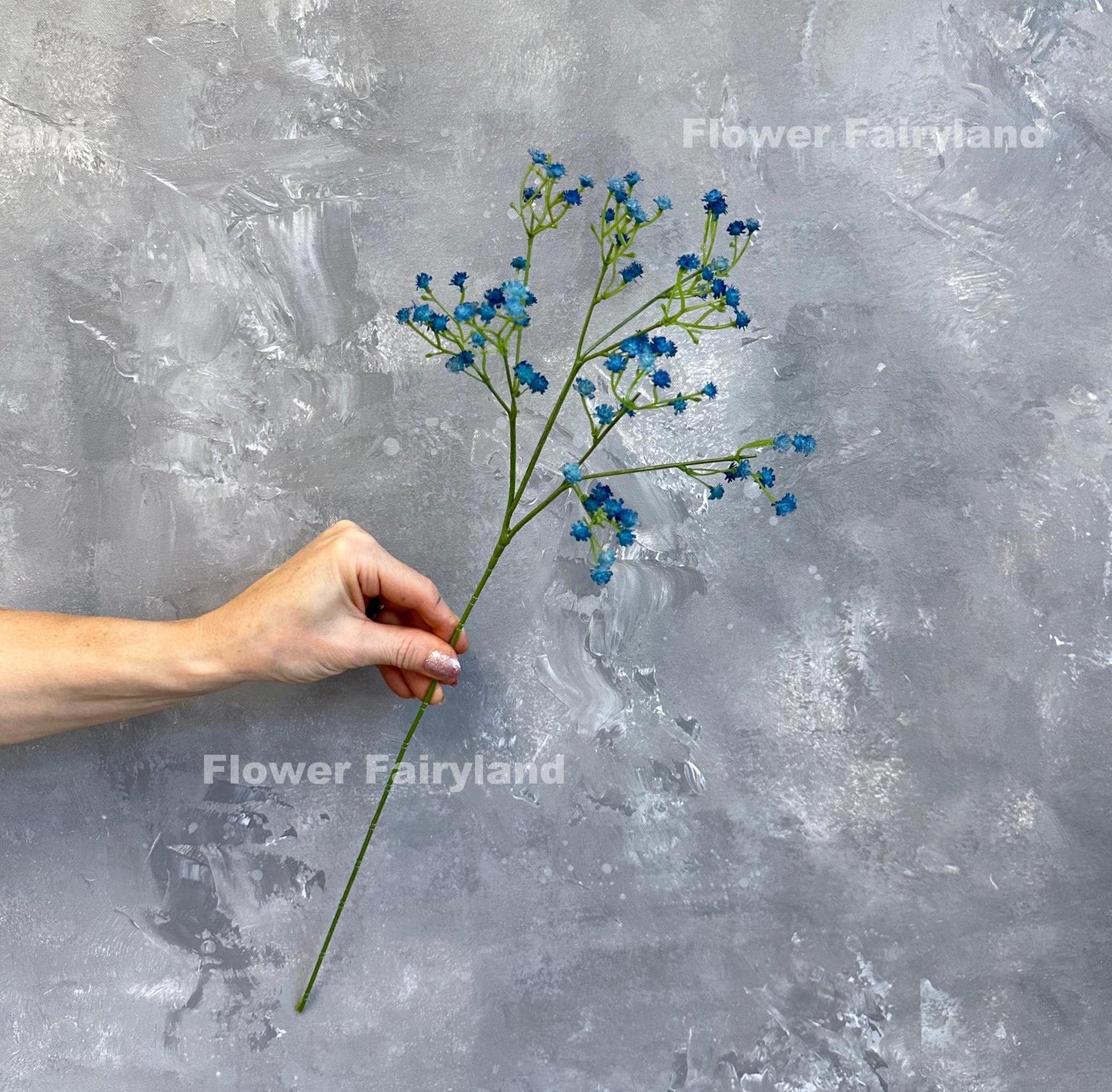 Dark blue faux baby's breath held in hand