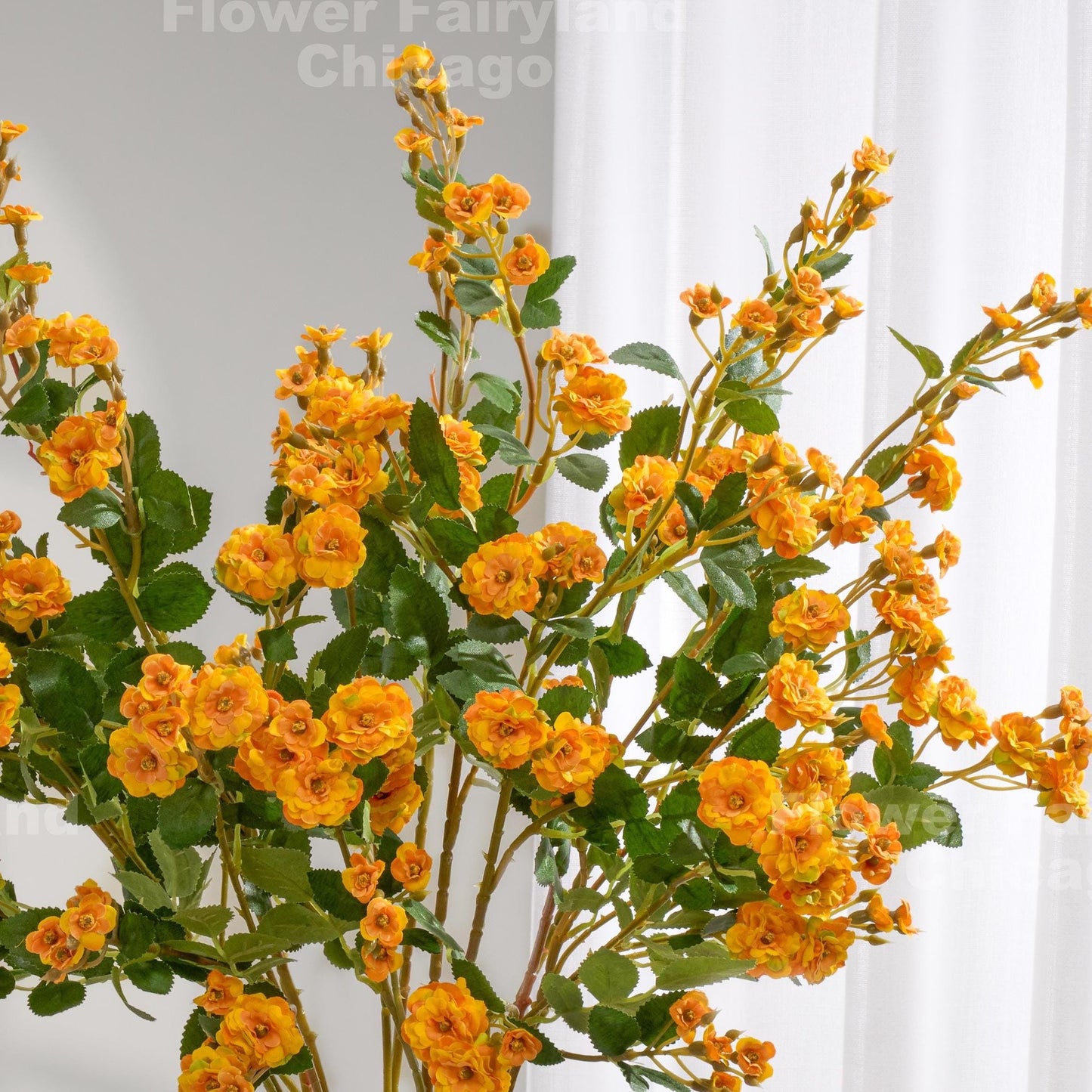 Yellowish orange faux miniature rose stems in a vase
