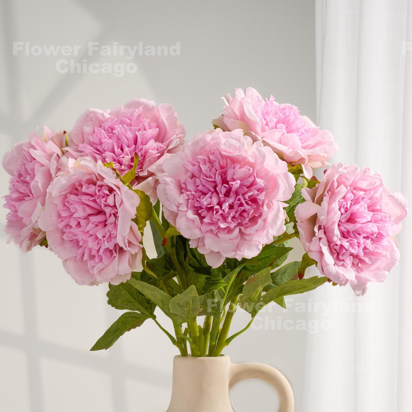 Light pink real touch peonies arranged in a cream vase