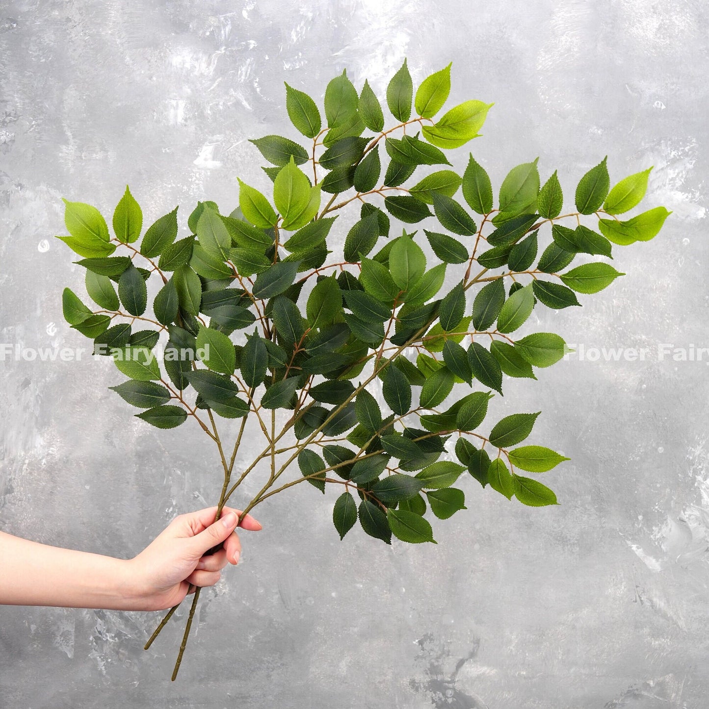 Faux ash branch in dark green held in hand