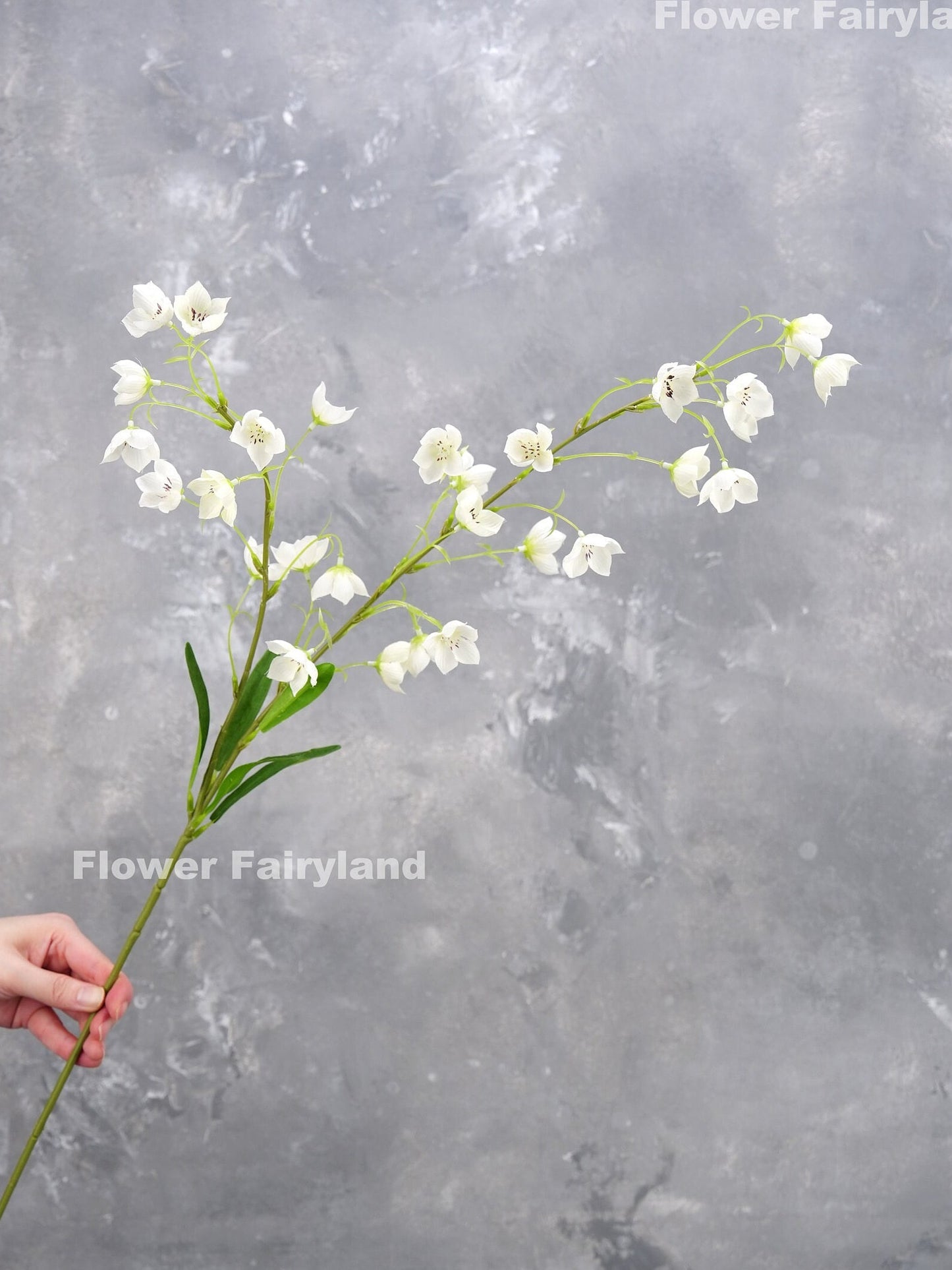 White faux Enkianthus stem held in hand