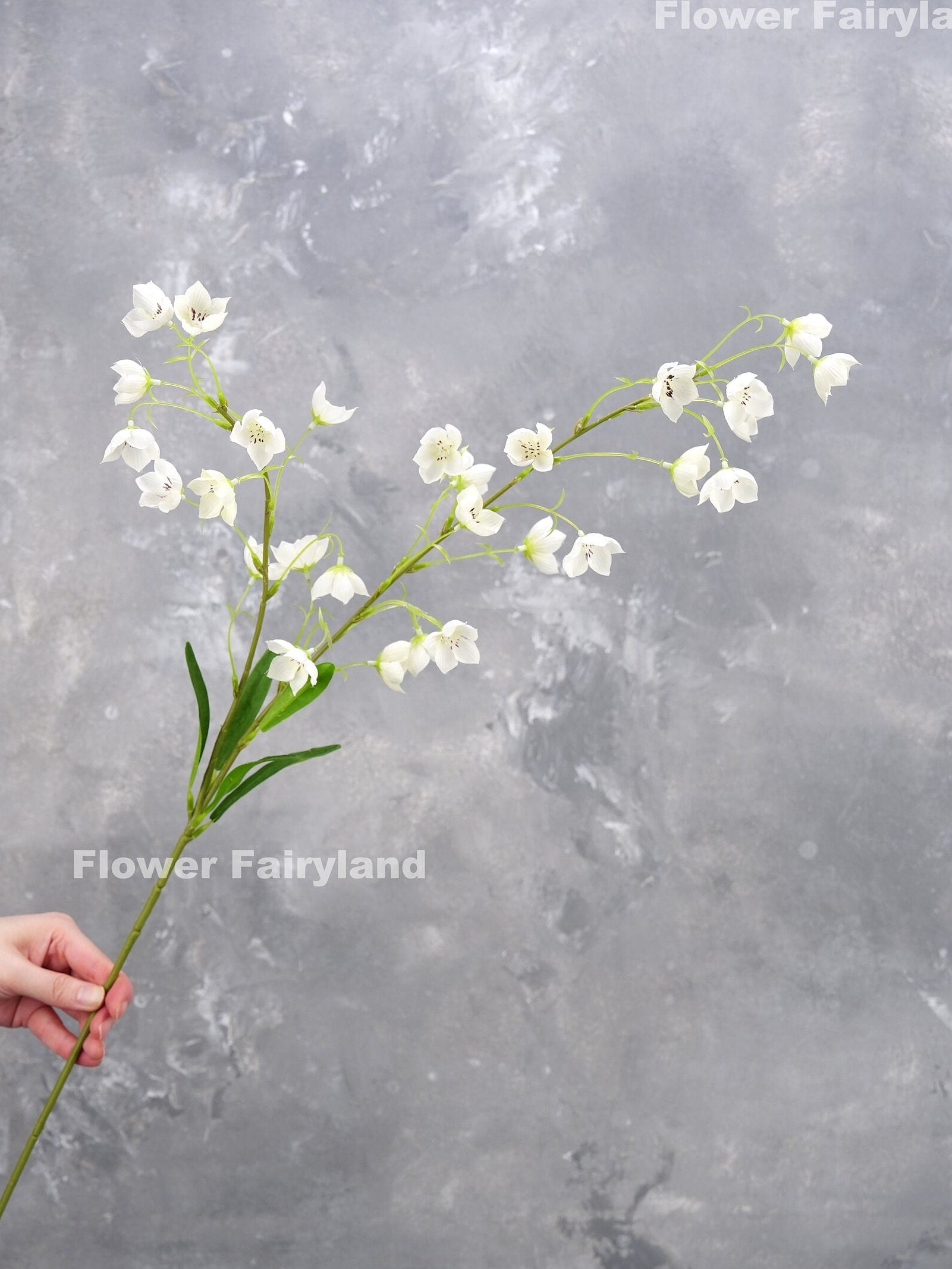 White faux Enkianthus stem held in hand
