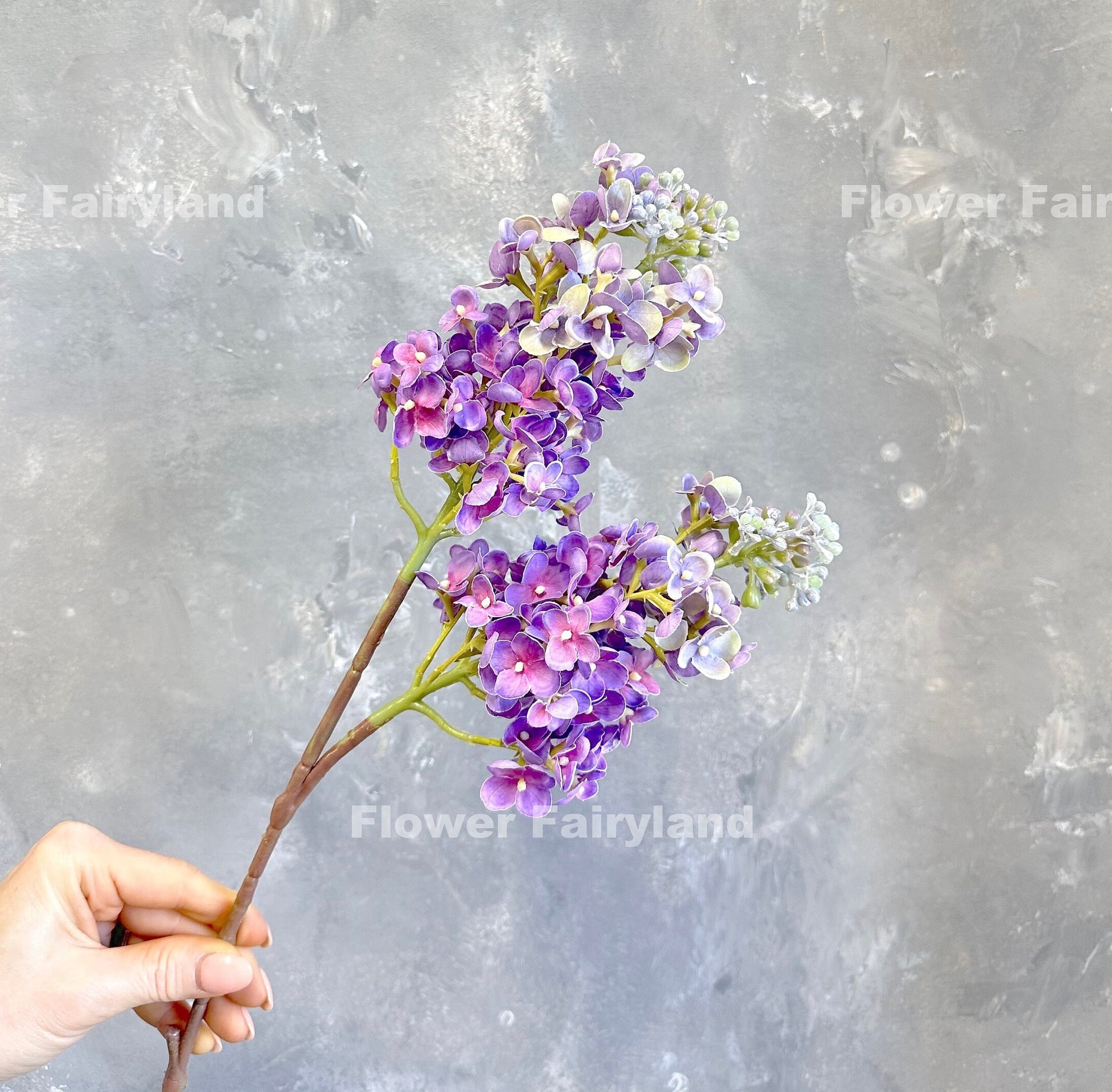 Single purple real touch lilac stem held in hand
