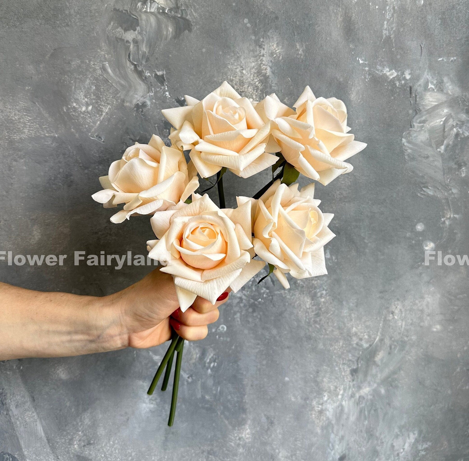Champagne peach rose bouquet in hand against gray backdrop