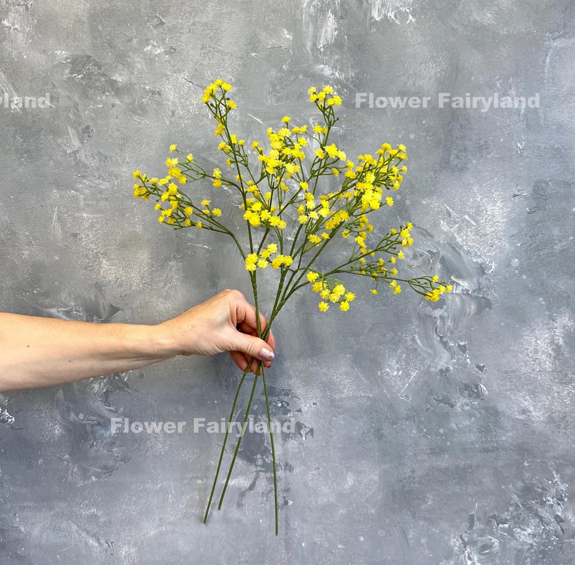 Yellow faux baby's breath held in hand
