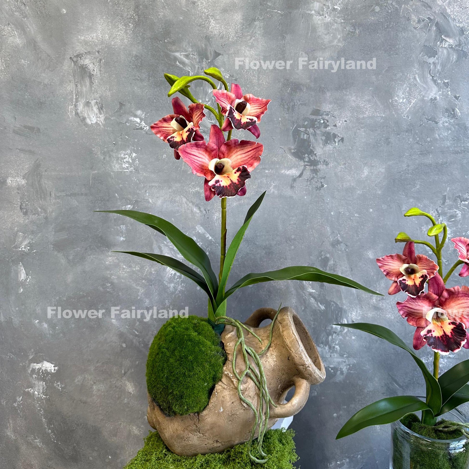 Light coral burgundy faux cattleya orchid held in hand