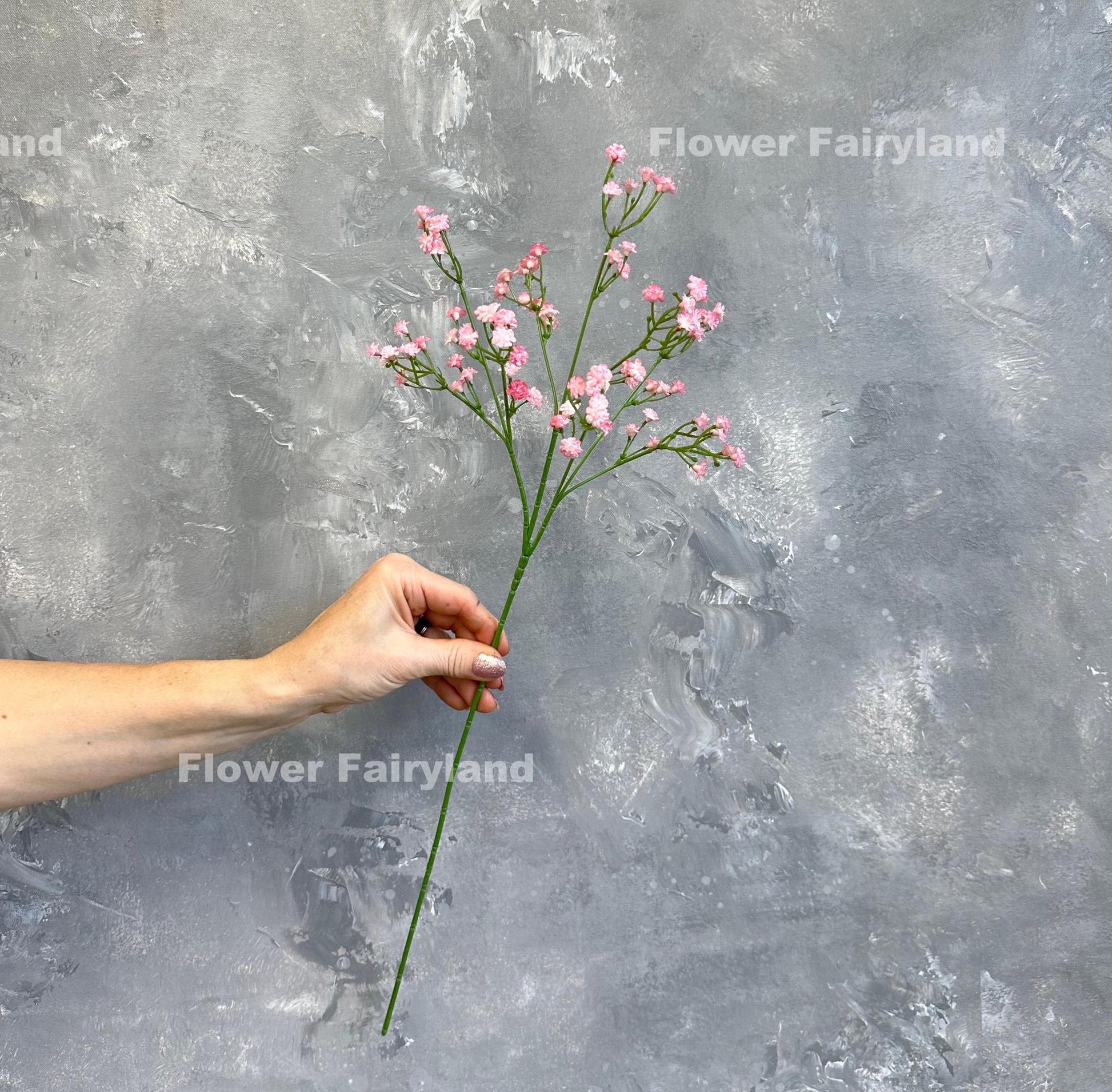 Pink faux baby's breath held in hand