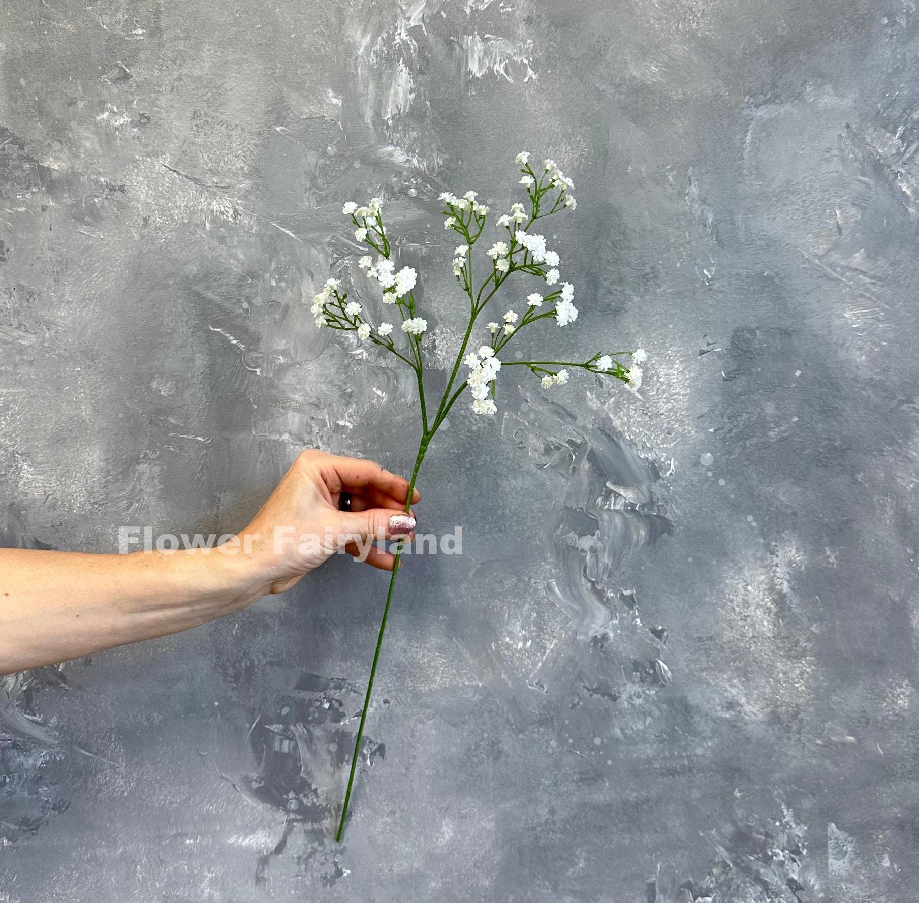 White faux baby's breath single stem held in hand