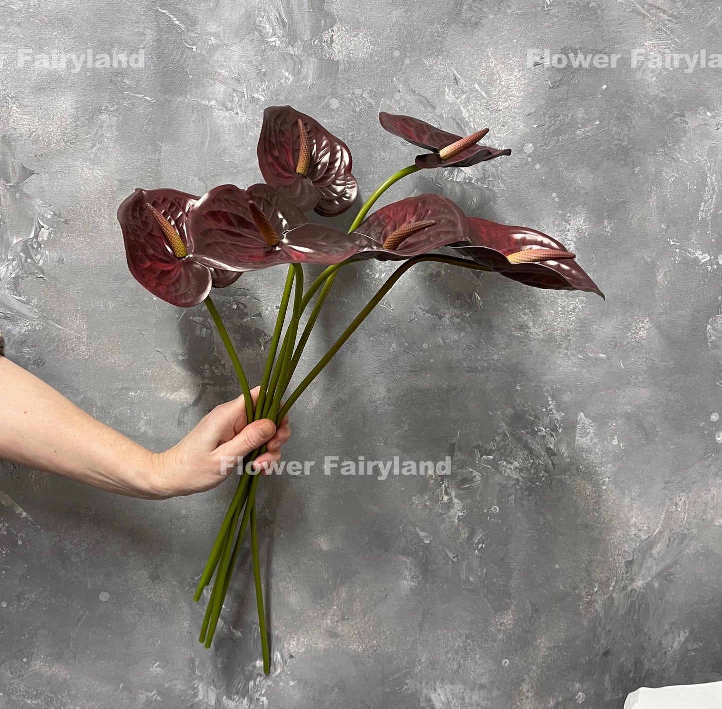 Burgundy real touch anthurium stem held in hand