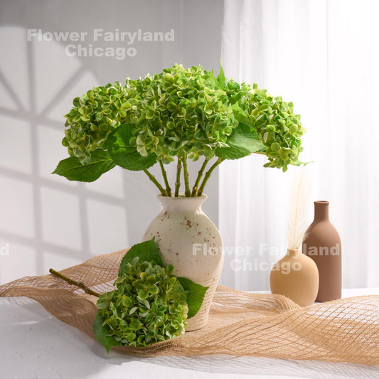 Green faux hydrangeas styled in a glass vase