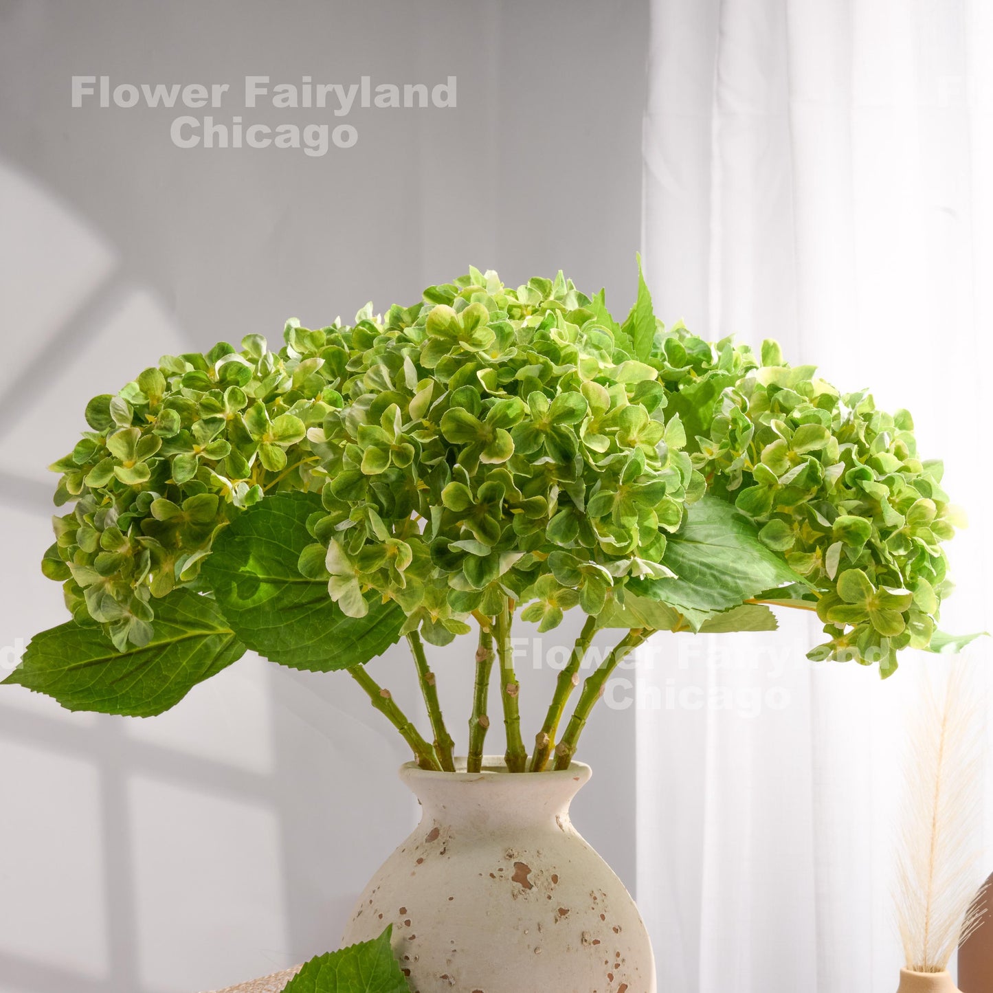 Green faux hydrangea arrangement in a vase