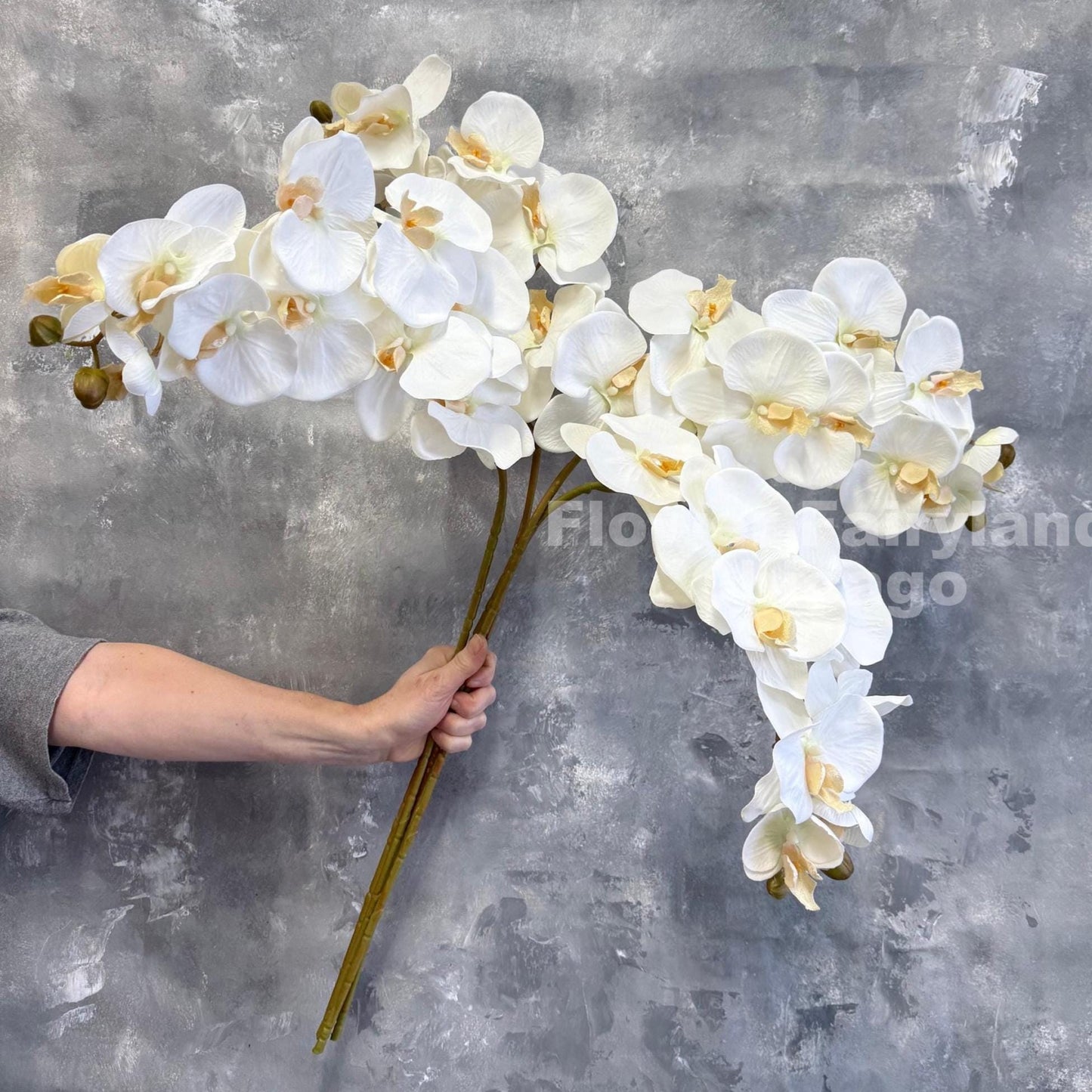 White faux orchid stem held in hand showing arch
