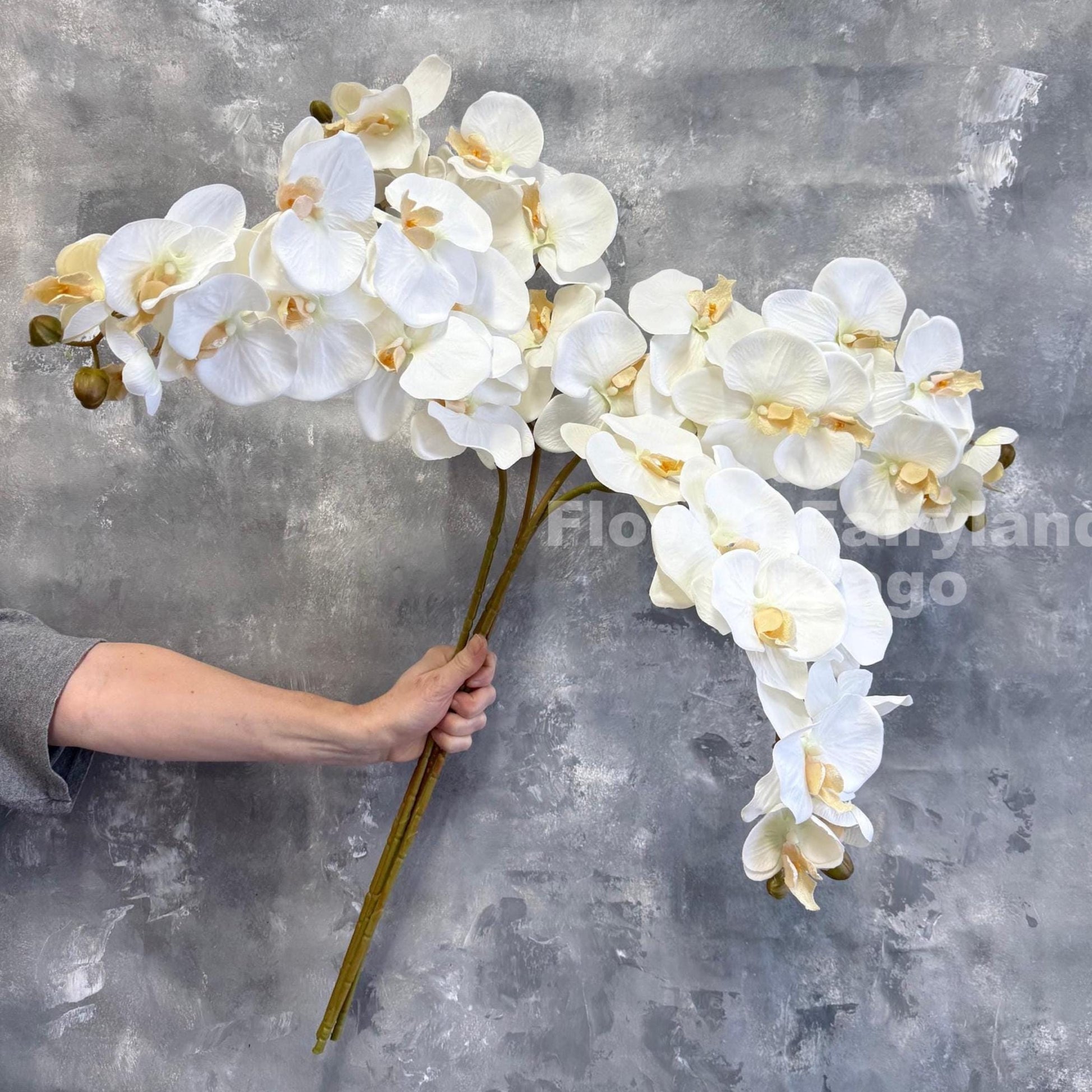 White faux orchid stem held in hand showing arch