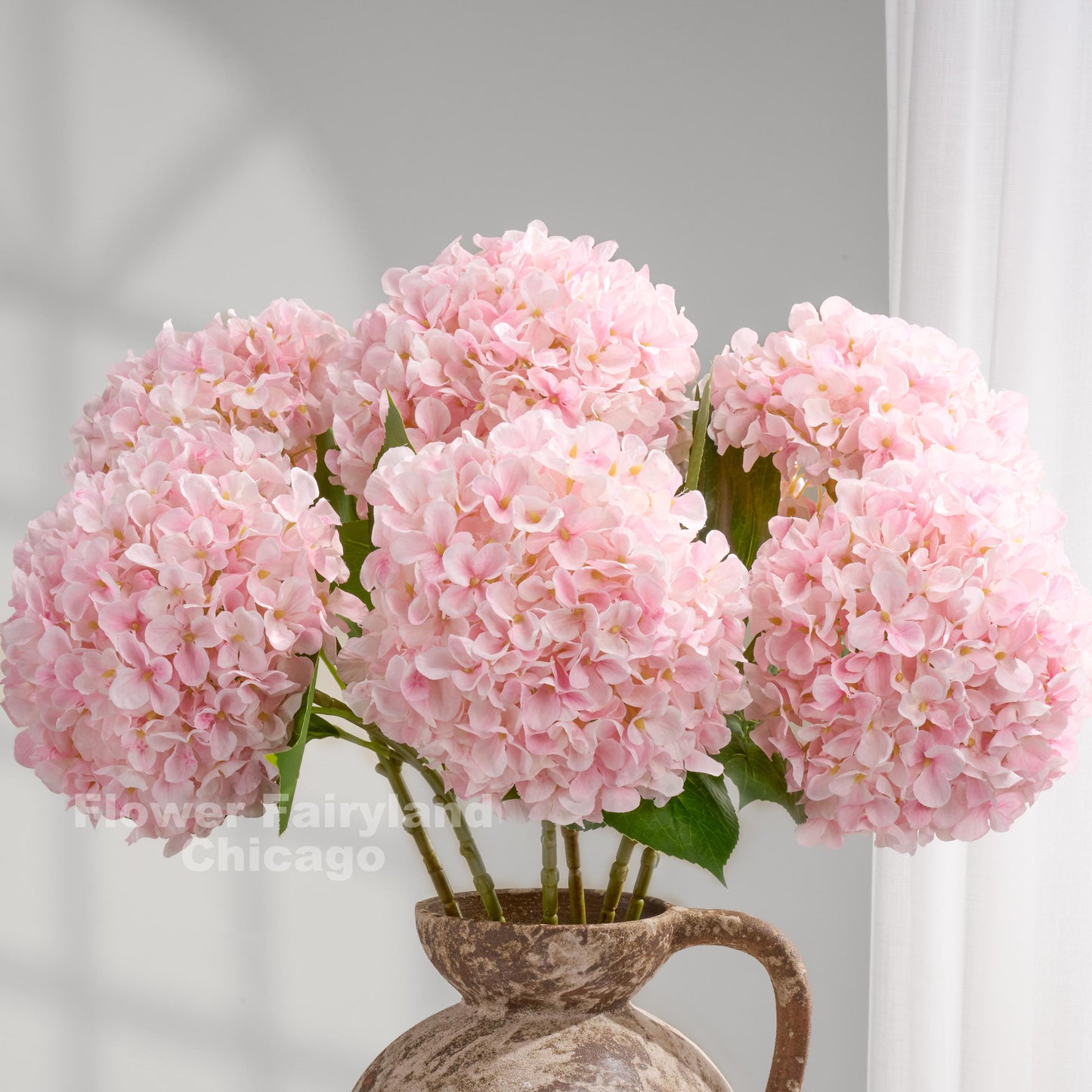 Light pink faux hydrangeas styled in a pitcher vase