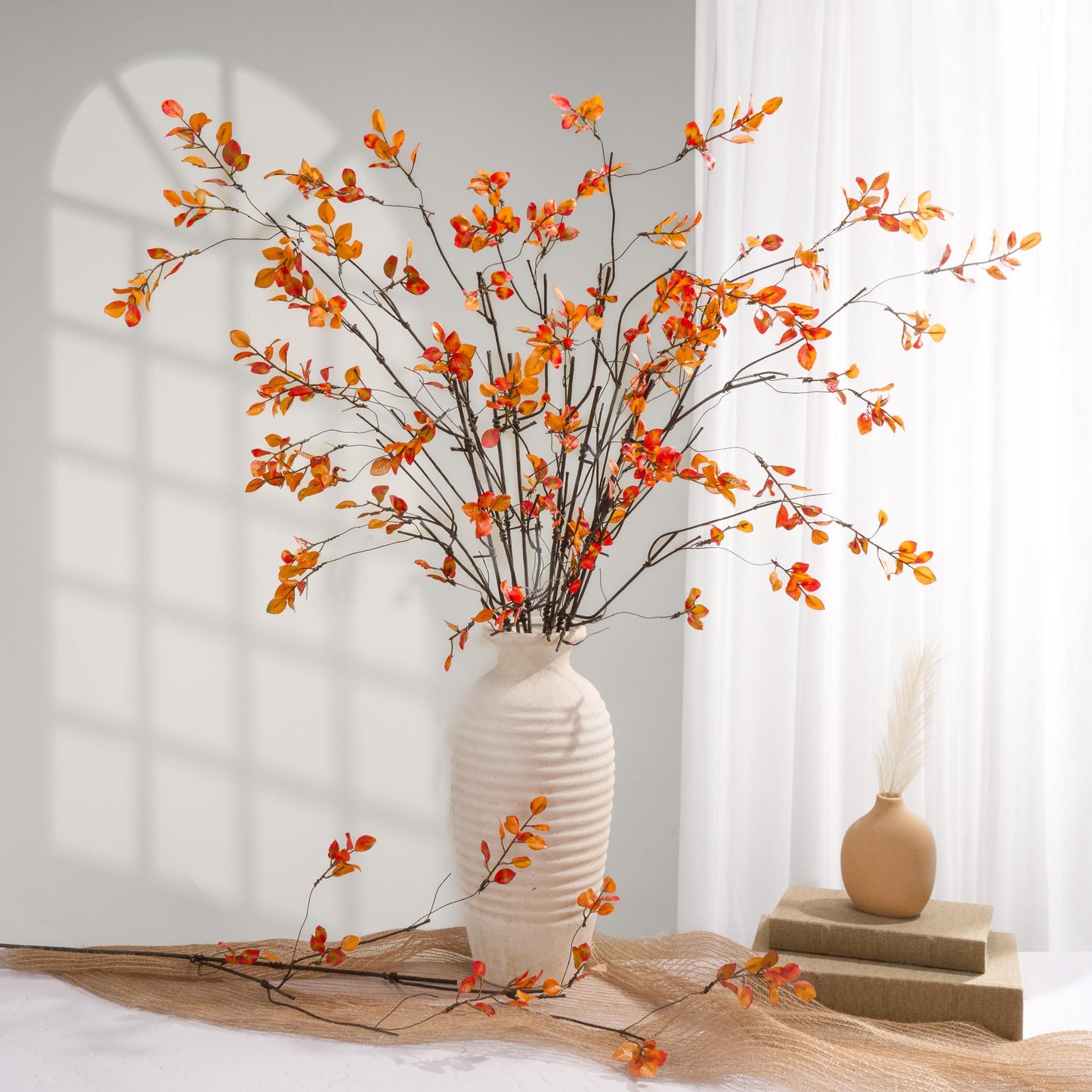 Orange faux leaf branches styled in a white vase