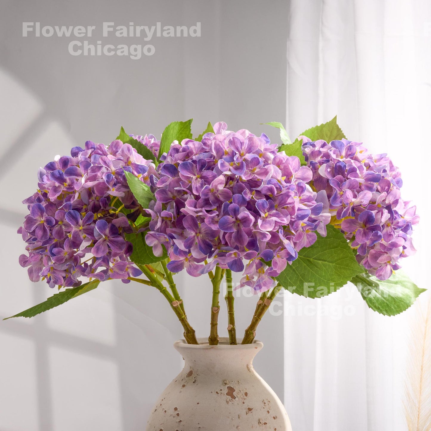 Purple faux hydrangeas styled in a pitcher vase