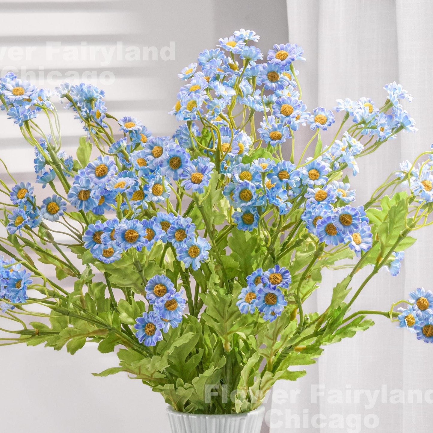 Blue faux chamomile styled in a vase with greenery