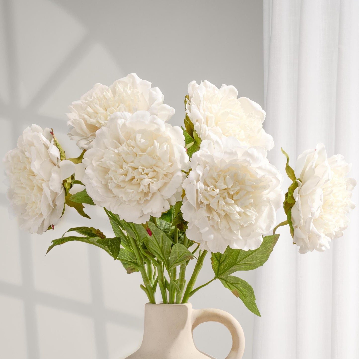 White real touch peonies arranged in a cream vase