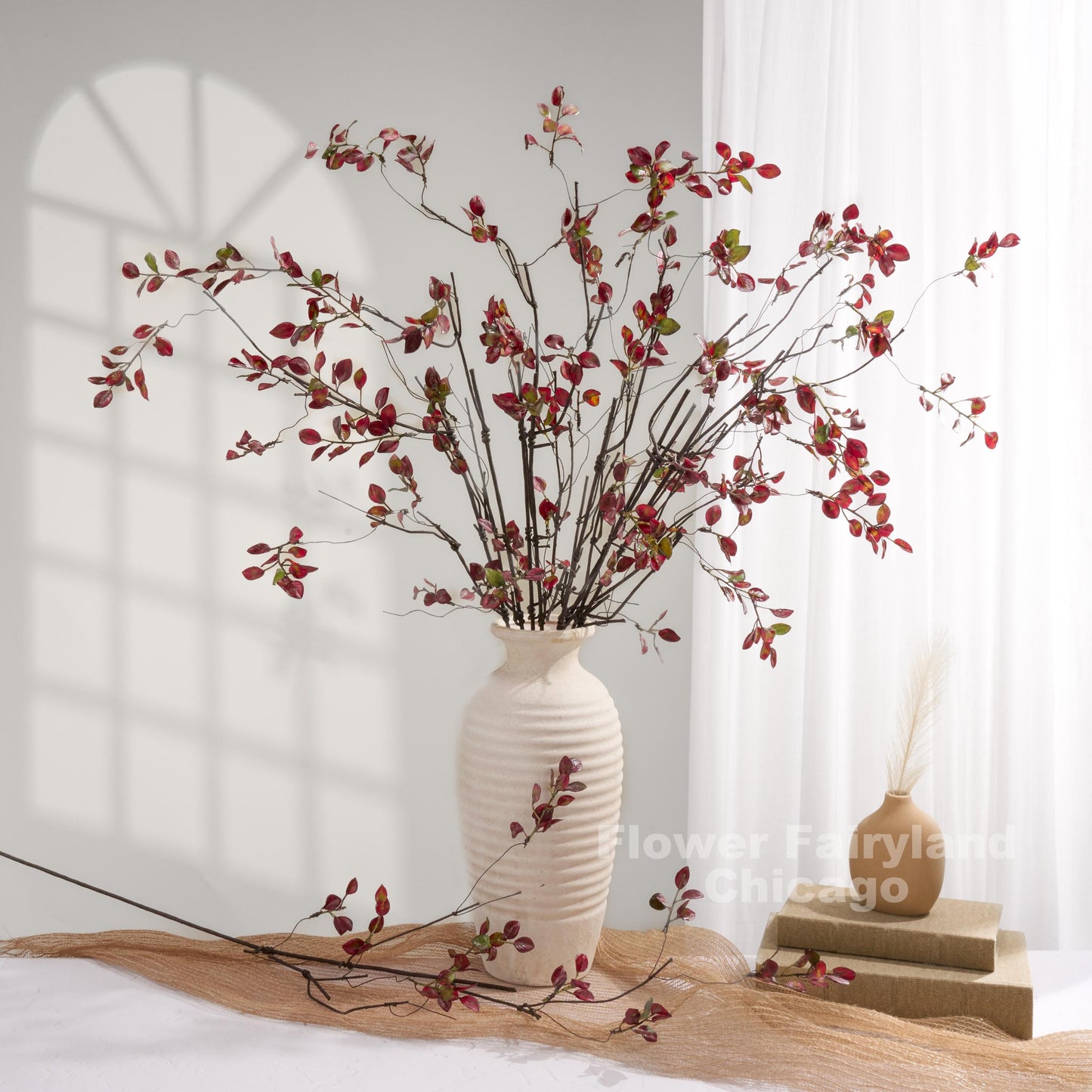 Burgundy leaf branches styled in a white vase