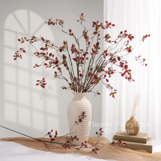Burgundy leaf branches styled in a white vase
