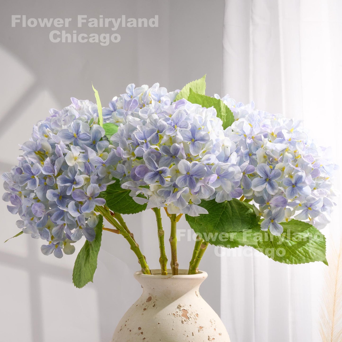 Light violet blue faux hydrangeas styled in a glass vase