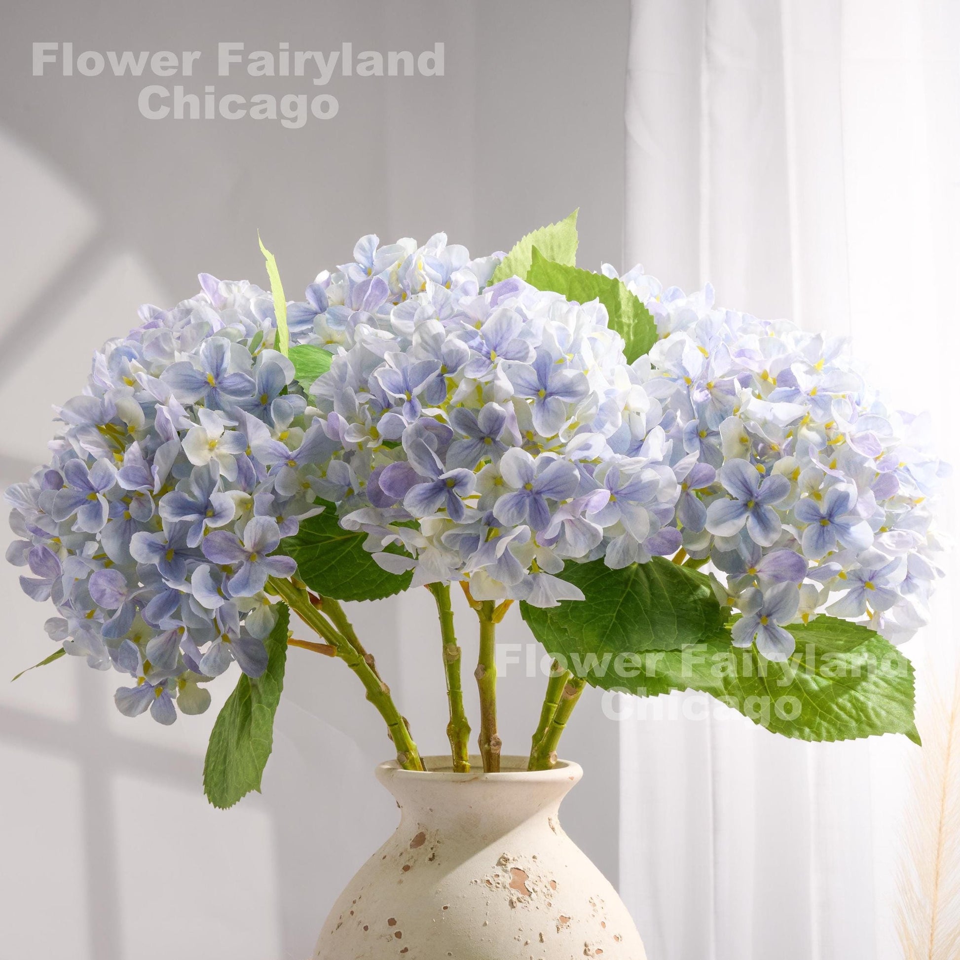 Light violet blue faux hydrangeas styled in a glass vase