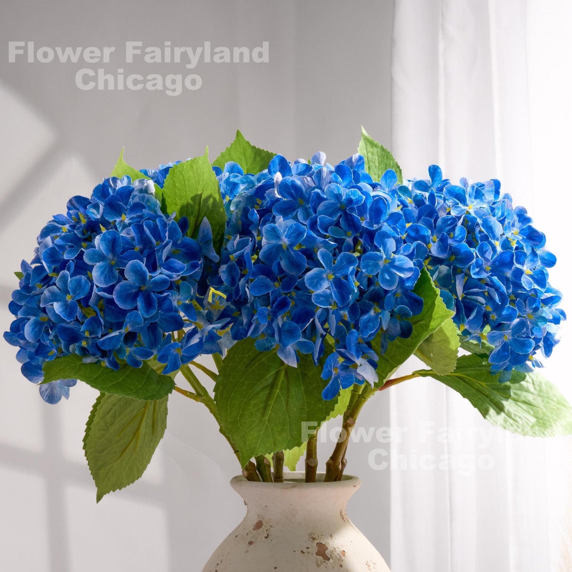 Dark blue faux hydrangeas styled in a pitcher vase