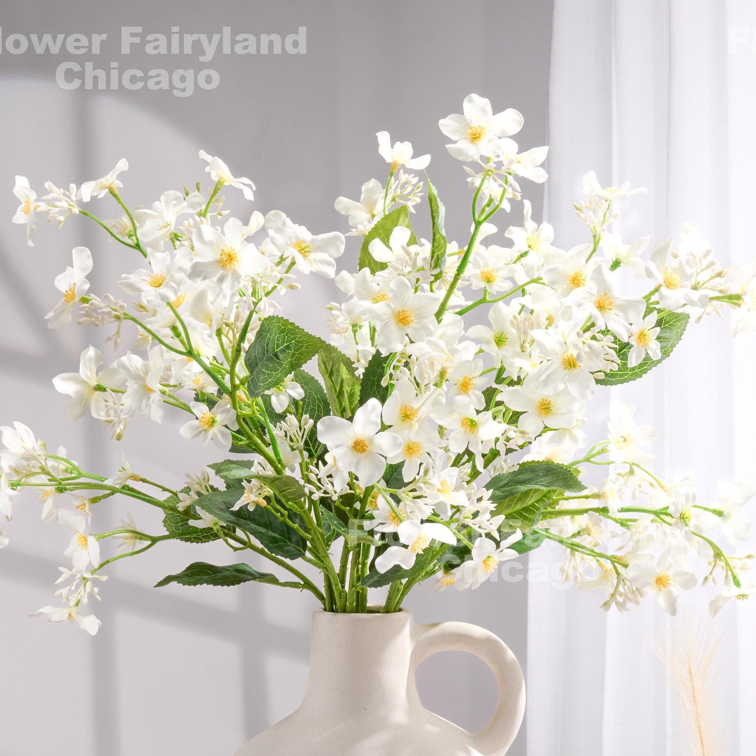 White faux Vernicia blossoms styled in a vase
