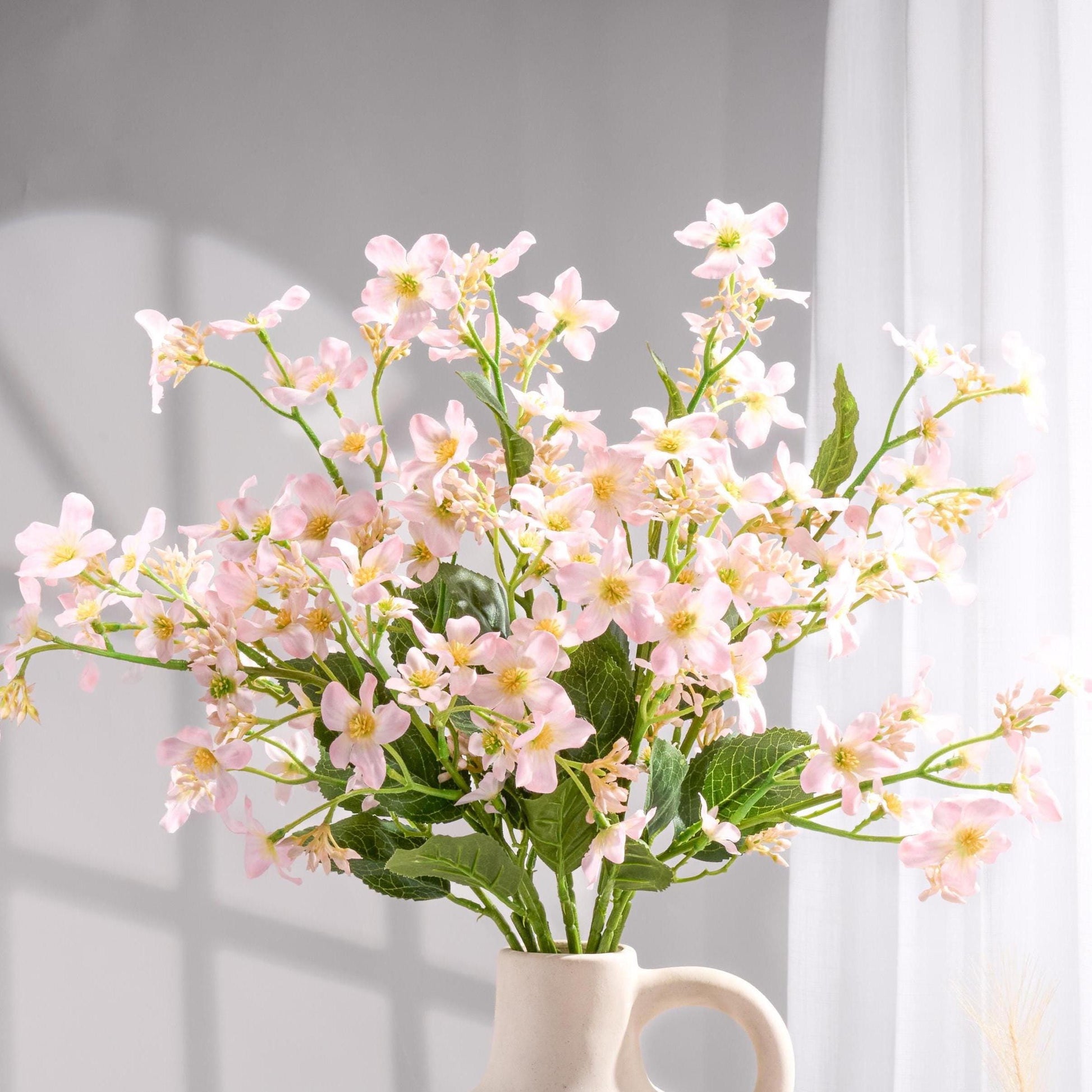 Light pink faux Vernicia blossoms styled in a vase