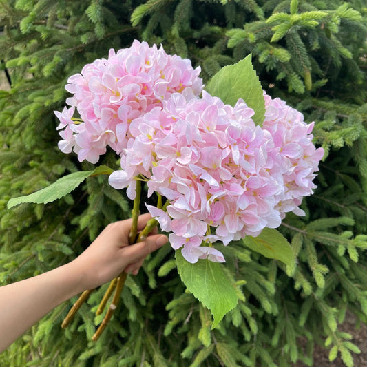 Faux hydrangea stem in light pink held in hand