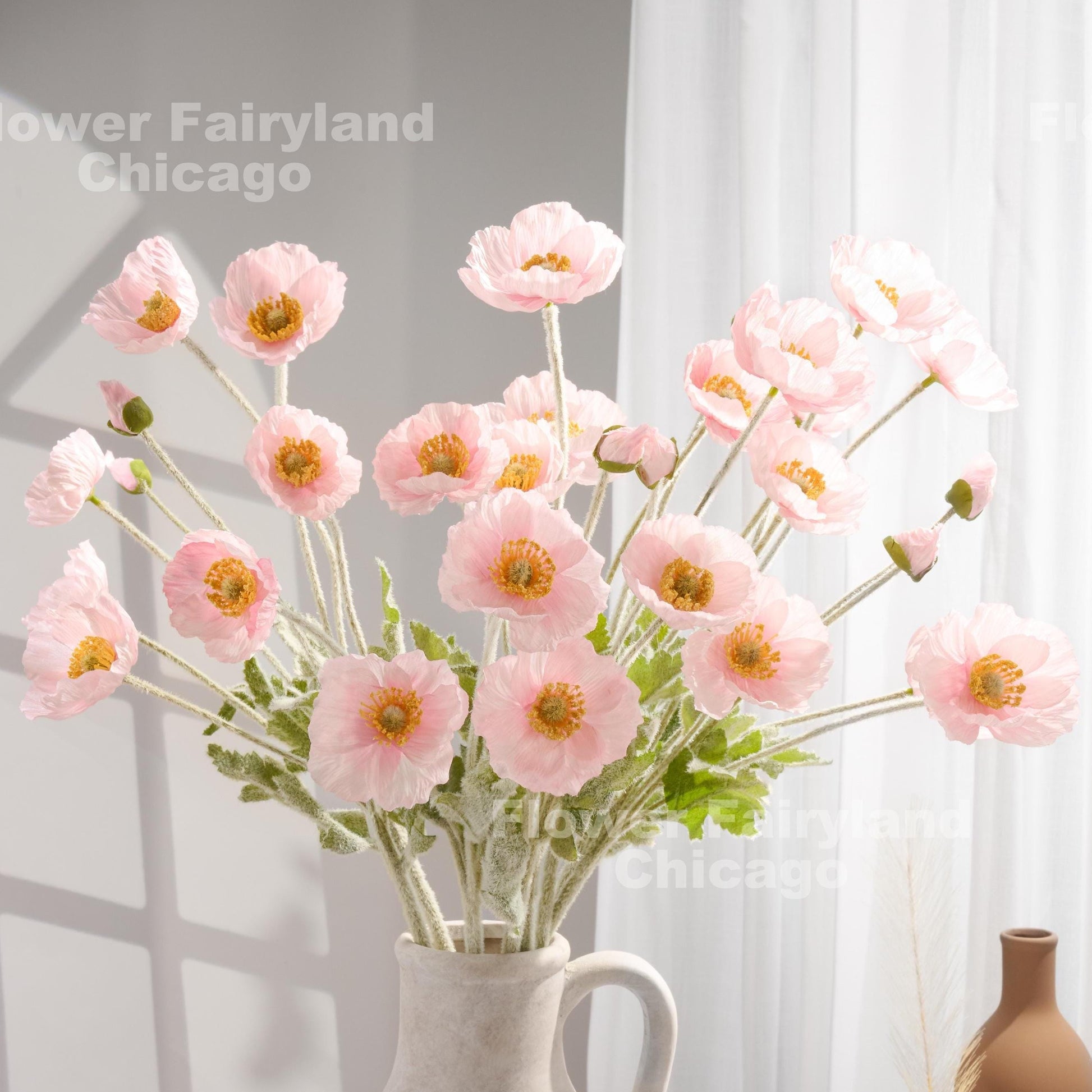 Soft pink faux poppy stems in a vase