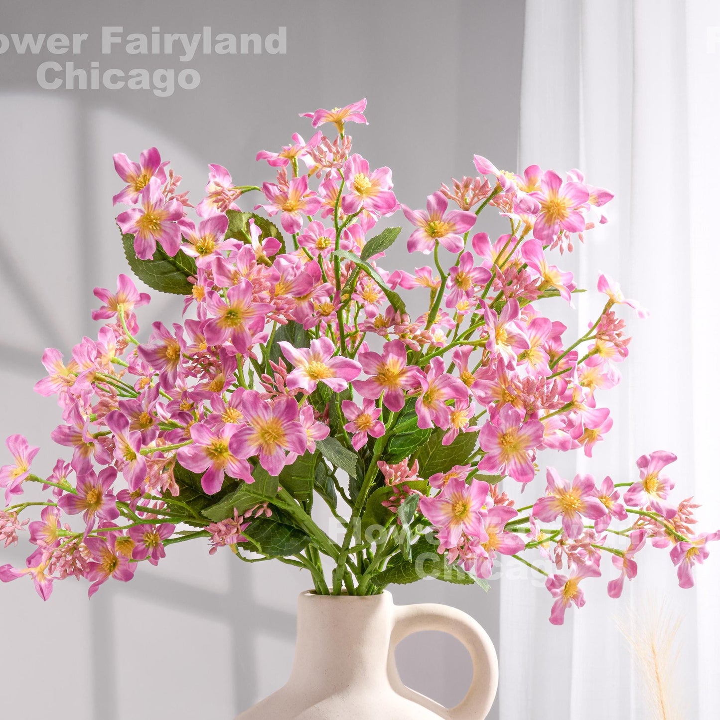 Pinkish lilac faux Vernicia blossoms styled in a vase