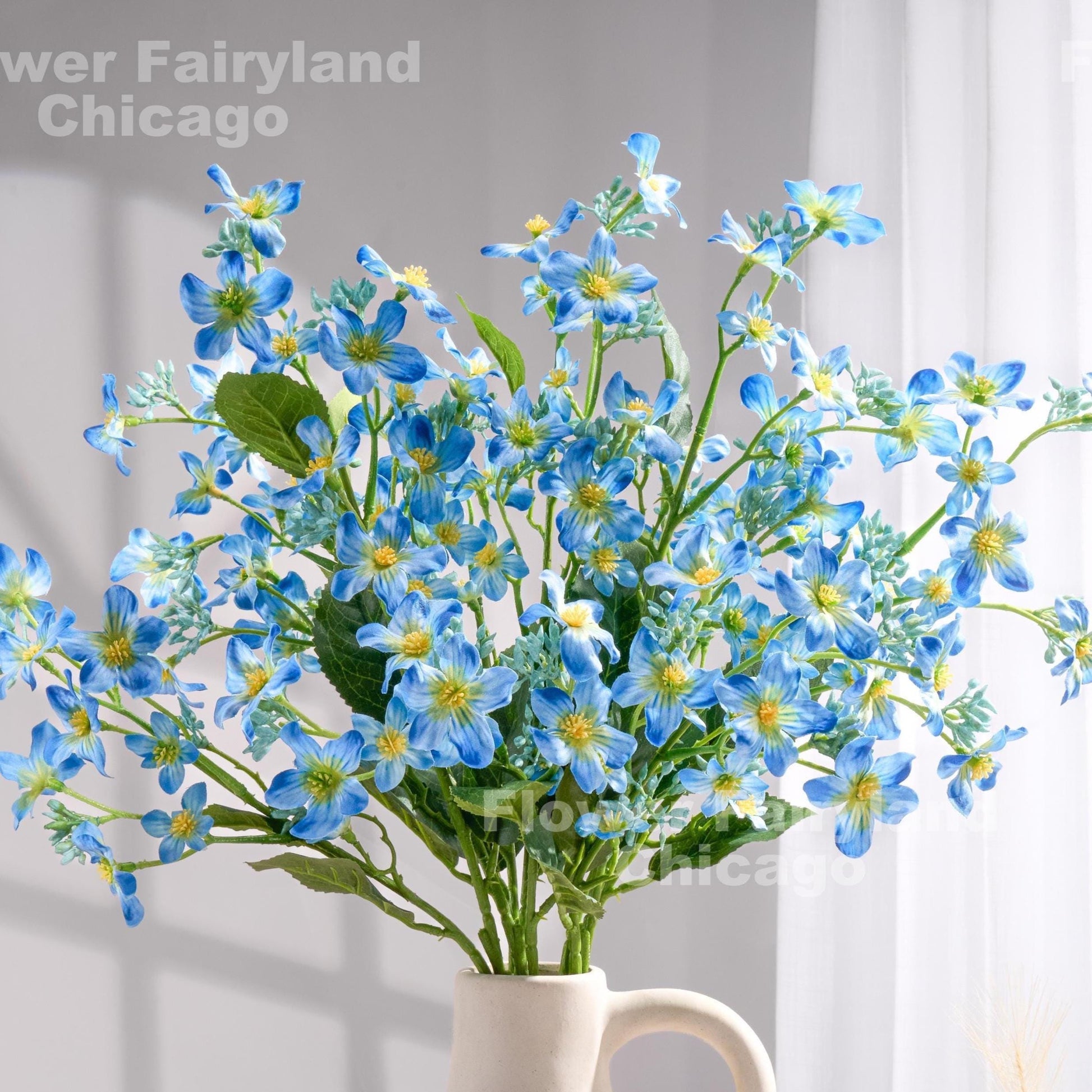 Blue faux Vernicia blossoms styled in a vase