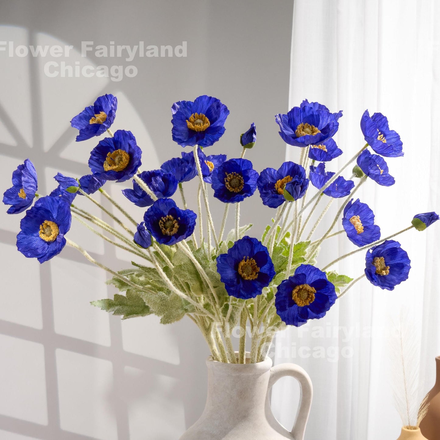 Royal blue faux poppy bouquet held in hand