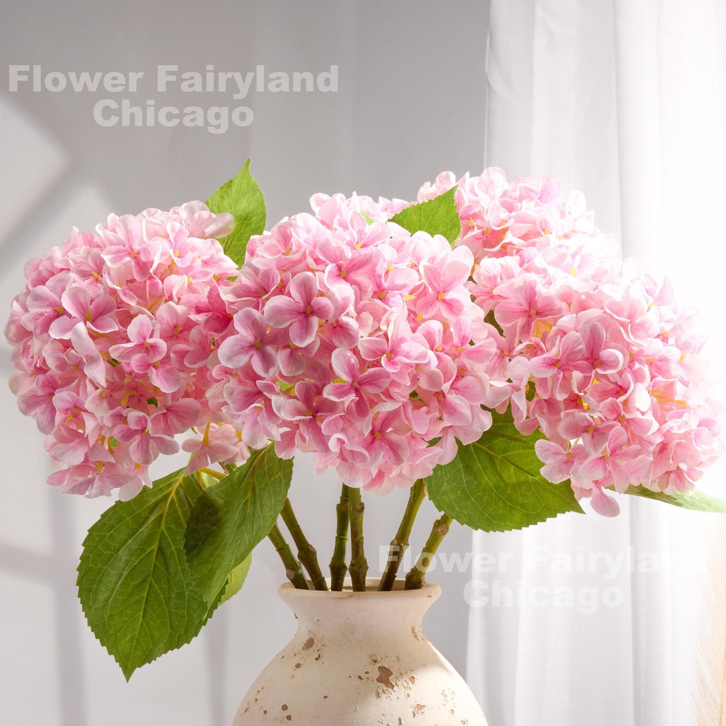 Pink faux hydrangeas styled in a glass vase