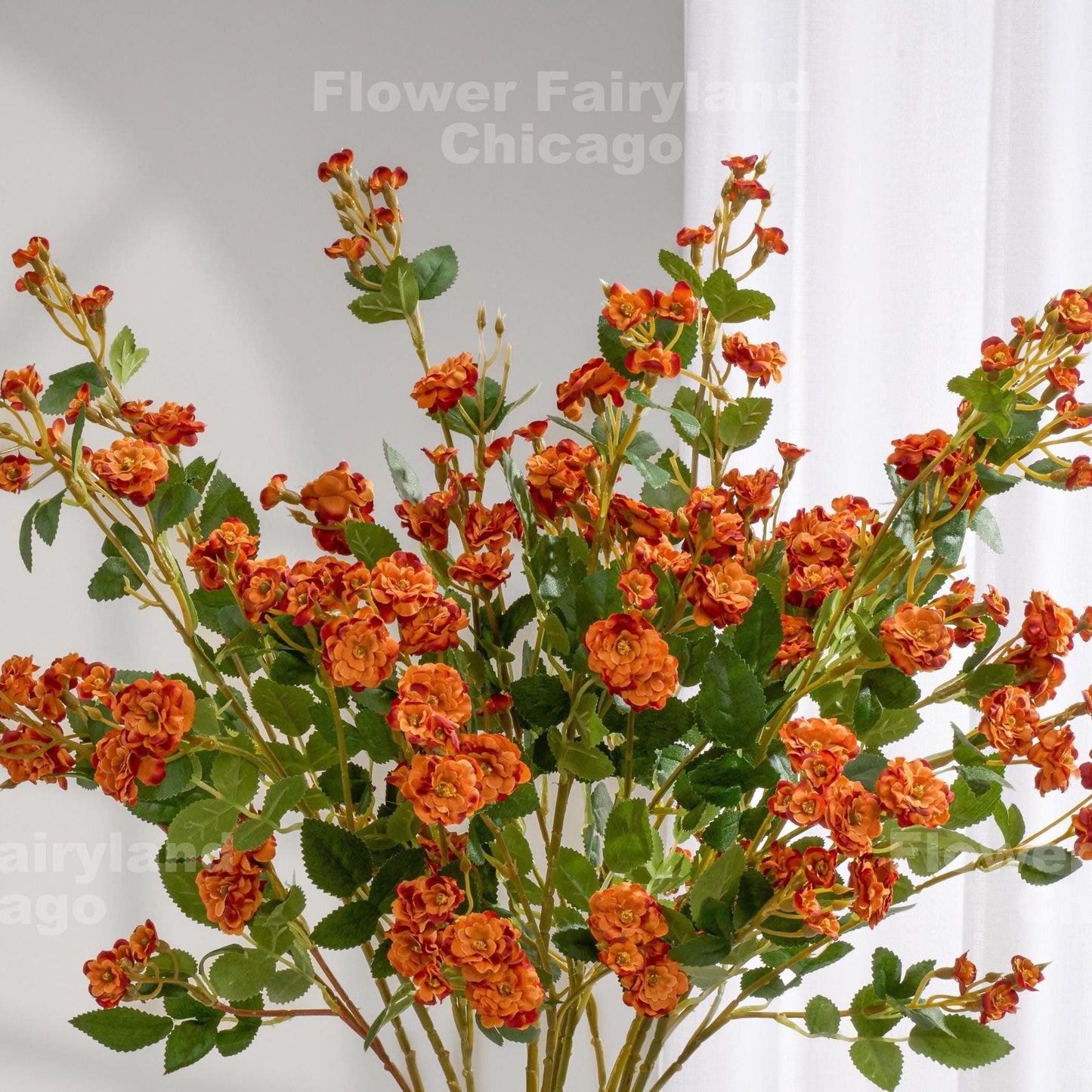 Dark burnt orange faux miniature rose stems in a vase