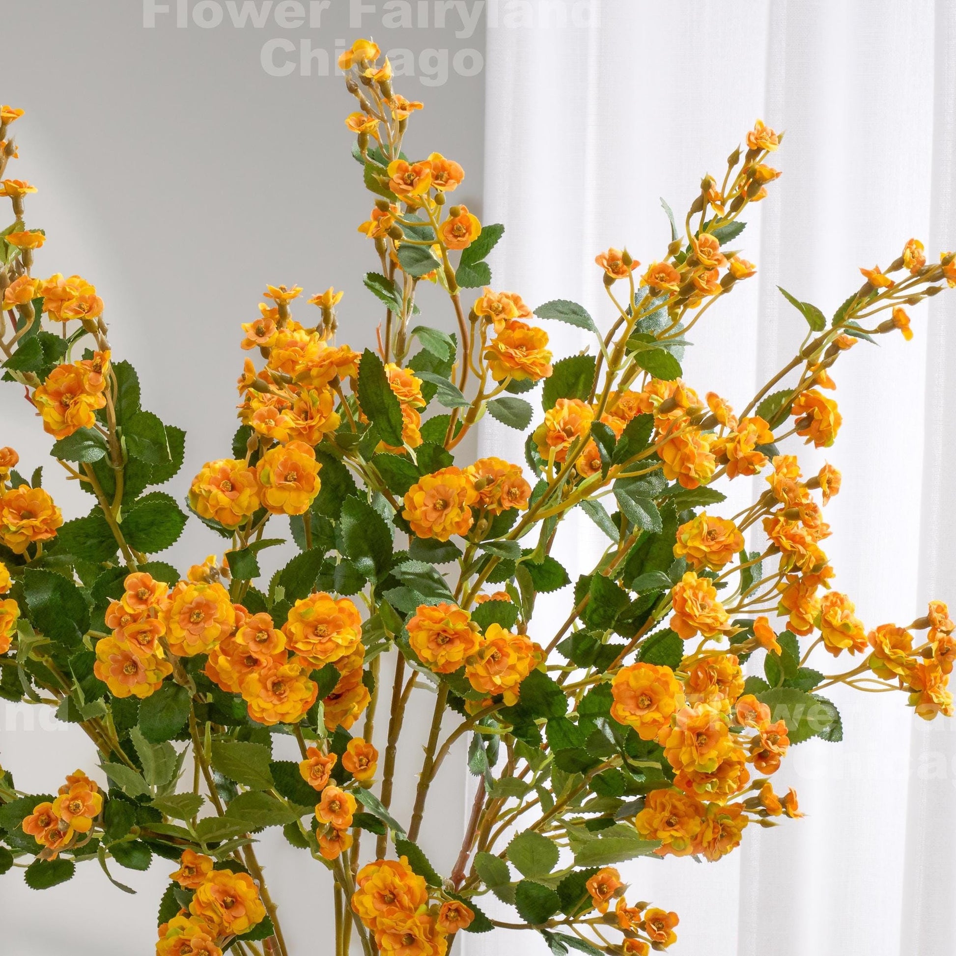 Yellowish orange faux miniature rose stems in a vase