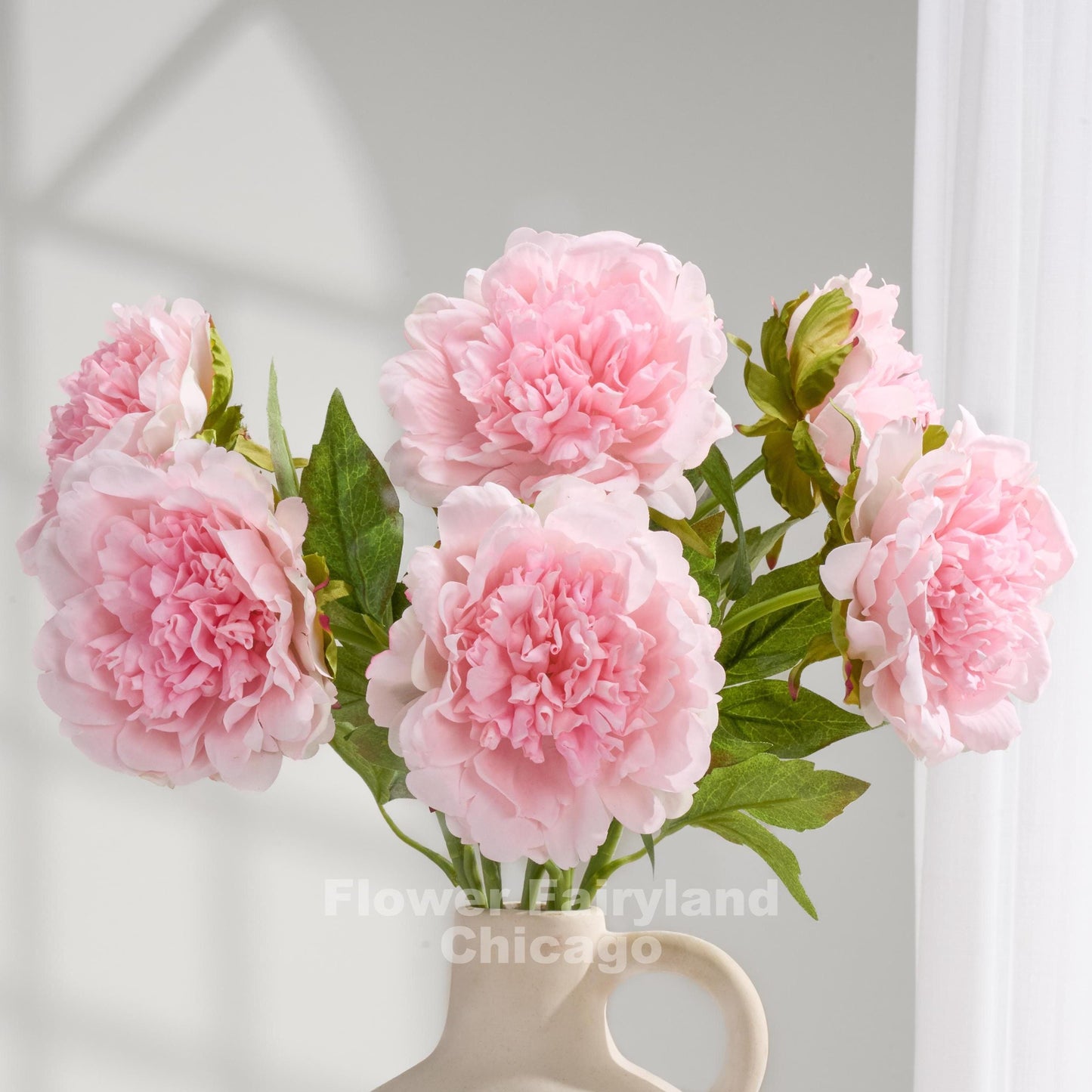 Baby pink real touch peonies arranged in a cream vase