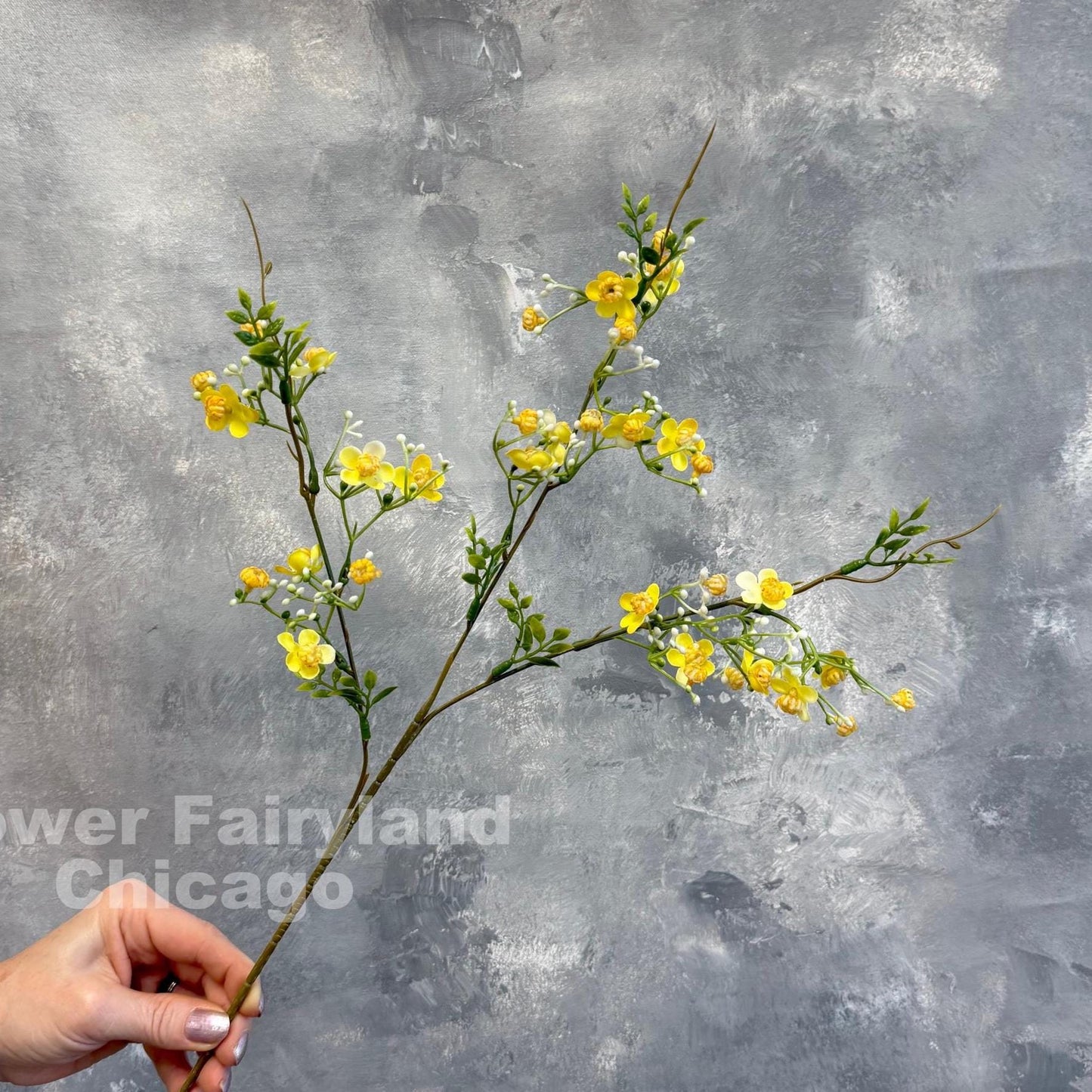 Yellow faux wax flower held in hand