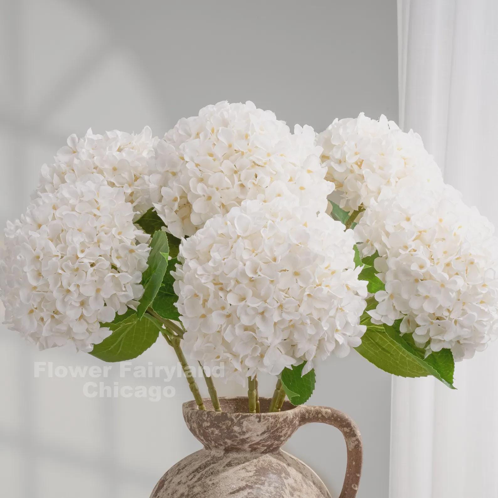 White faux hydrangeas in a pitcher vase